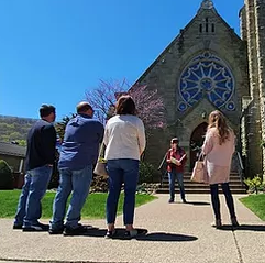 A group of people listen to a tour guide outside a historic building